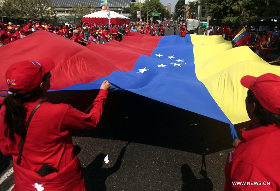 Residents hold a national flag during the closing campaign of Venezuelan acting president and presidential candidate Nicolas Maduro in the city of Caracas, capital of Venezuela, on April 11, 2013. (Xinhua/AVN) 