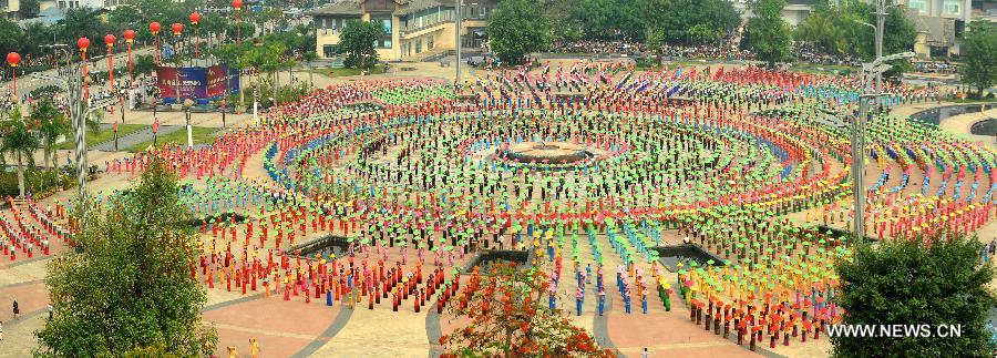 People gather on a square performing a traditional umbrella dance to celebrate the Water Splashing Festival, also the New Year of the Dai ethnic group, in Jinghong City, Dai Autonomous Prefecture of Xishuangbanna, southwest China's Yunnan Province, April 14, 2013. (Xinhua/Qin Qing)  