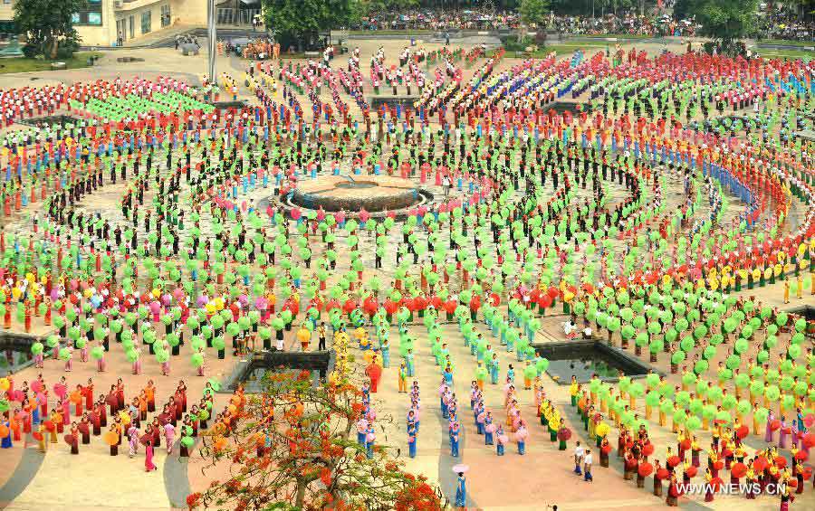 People gather on a square performing a traditional umbrella dance to celebrate the Water Splashing Festival, also the New Year of the Dai ethnic group, in Jinghong City, Dai Autonomous Prefecture of Xishuangbanna, southwest China's Yunnan Province, April 14, 2013. (Xinhua/Qin Qing)  