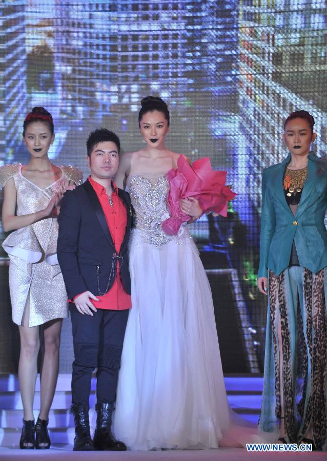 Chinese designer Qi Gang (2nd L) poses with models in Beijing, capital of China, April 13, 2013. (Xinhua/Wang Jingguang)