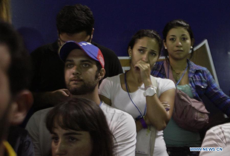 Followers of Venezuelan opposition presidential candidate Henrique Capriles react after the election results were announced in Caracas, capital of Venezuela, on April 14, 2013. Venezuelan acting President Nicolas Maduro narrowly won the presidential election with 50.66 percent of the votes, National Electoral Council's President Tibisay Lucena said on Sunday. (Xinhua/Juan Carlos Hernandez)