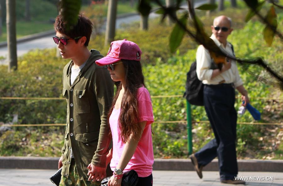 People walk in a park in Xujiahui area of Shanghai, east China, April 15, 2013. The temperature in Shanghai's Xujiahui area reached 30.2 degrees Celsius due to a warm air mass over it on Monday, according to local meteorological station. (Xinhua/Pei Xin) 