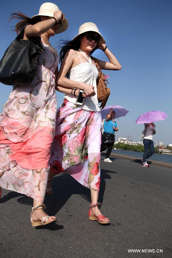 Visitors in summer wear walk on Bai Causeway over the West Lake in Hangzhou, capital of east China's Zhejiang Province, April 15, 2013. The temperature in Hangzhou Monday approached 33 degrees Celsius, a record high at this time of year since 1951. (Xinhua/Shao Quanhai)