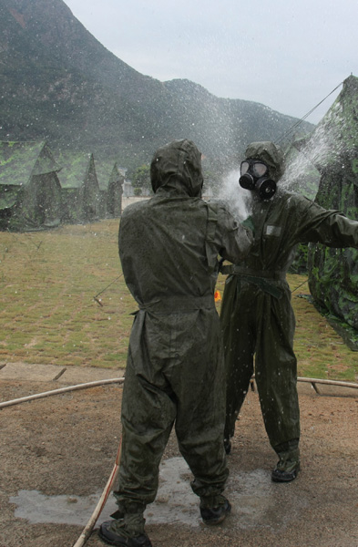 A shore-based mobile anti-ship-missile regiment under the South China Sea Fleet of the Navy of the Chinese People's Liberation Army (PLA) organized a NBC (nuclear, biological and chemical) defense drill against actual-combat background on April 7, 2013. The picture shows the officers and men of the regiment are carrying out decontamination and detection of chemical agents in the infected "toxic" areas. (China Military Online/Sheng Yuehua, Zhao Changhong and Zheng Can)