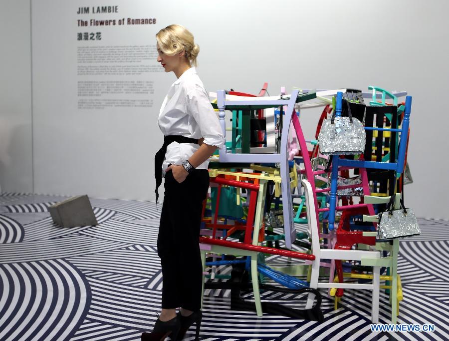 A visitor poses for a photo at the "Flowers of Romance" Installation Art Exhibition by British visual artist Jim Lambie in Hong Kong, south China, April 16, 2013. (Xinhua/Li Peng) 