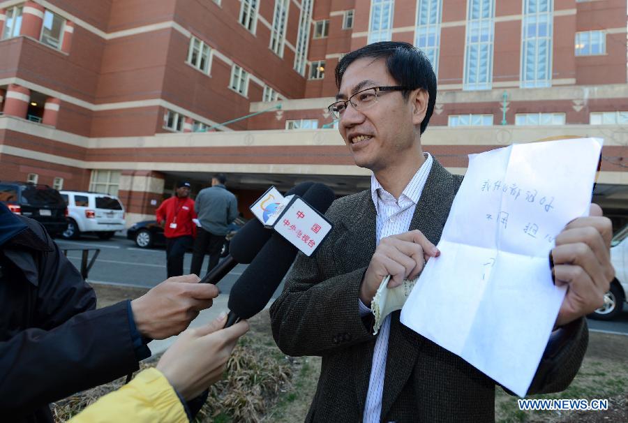 Chinese Vice Counselor-General Zhong Ruiming (R) of the Chinese Consulate General in New York shows words written by injured Chinese student Zhou Danling at the Boston Medical Center in Boston, the United States, April 16, 2013. The words read "Everything is fine. Don't Worry." Zhou, who was injured during the Boston marathon blasts, turned into better condition from critical one after receiving two surgeries. (Xinhua/Wang Lei) 