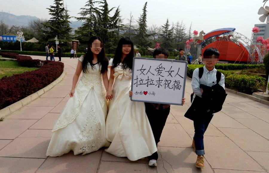 Lesbian lovers hold a wedding ceremony in a park of Lanzhou on April 15, 2012. They held a sign reading "Woman loves woman, lesbians need bless" to call for tolerance of homosexual marriage. 