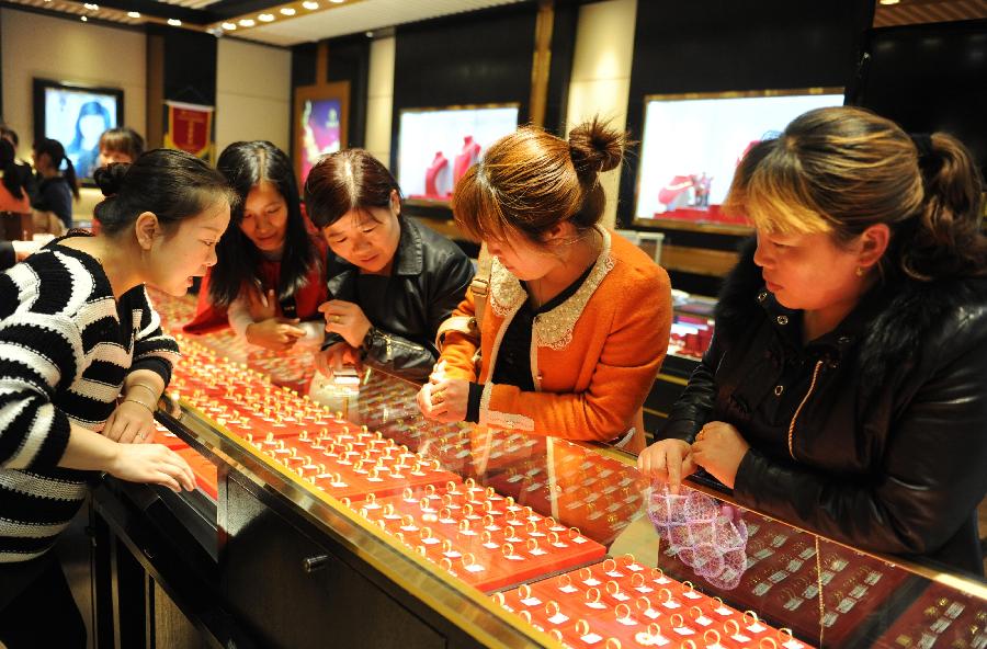Consumers select gold finger rings at a gold jewellery shop in Fuyang, east China's Anhui Province, April 18, 2013. Gold jewellery shops through China have lowered price of gold jewellery due to the consecutive decline of gold price global markets recently, which boost sales in these shops. (Xinhua)  