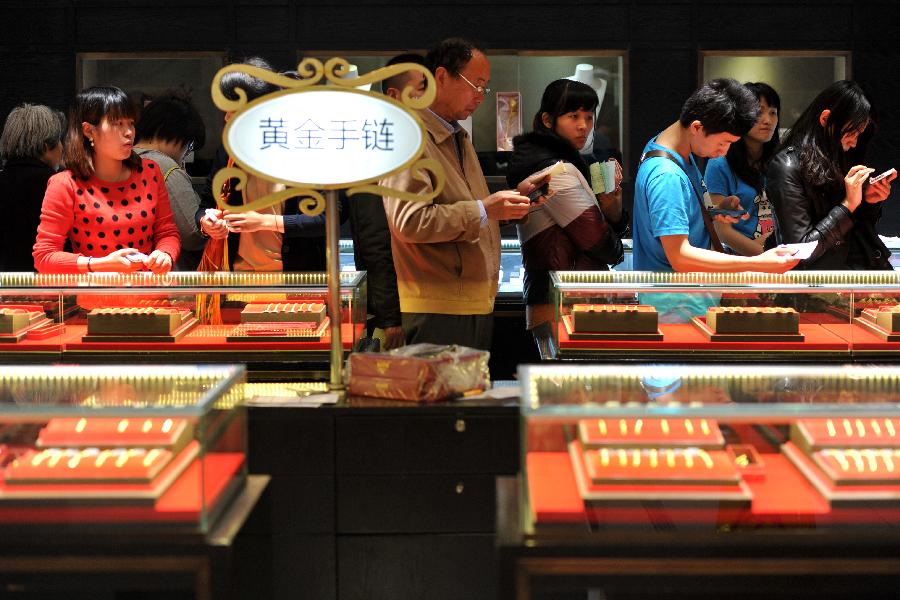 Consumers wait in a line to check out at a gold jewellery shop in Nanjing, capital of east China's Jiangsu Province, April 18, 2013. Gold jewellery shops through China have lowered price of gold jewellery due to the consecutive decline of gold price global markets recently, which boost sales in these shops. (Xinhua) 