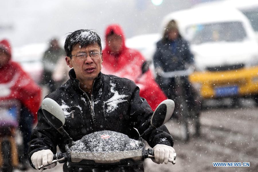 A citizen braves snow to ride on a snowy road in Taiyuan, capital of north China's Shanxi Province, April 19, 2013. The city witnessed a snowfall on April 19 morning. (Xinhua/Fan Minda)