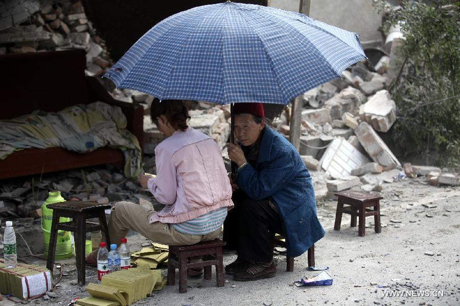 Displaced residents rest next to ruins of houses after a 7.0-magnitude earthquake in Longmen Township, Lushan County, Ya'an City of southwest China's Sichuan Province, April 20, 2013. At least 102 people were killed in the earthquake in Sichuan, according to the China Earthquake Administration on Saturday afternoon. (Xinhua/Zhang Xiaoli) 