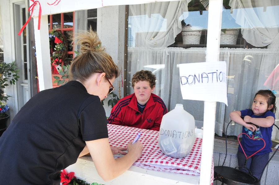 A woman writes a check for donation in West, Texas, the United States, April 20, 2013. The Authorities of the city of West, the U.S. state of Texas, on Saturday declared to impose curfew while allowing some of the evacuated residents to return home in the afternoon, more than two days after a powerful explosion at a local fertilizer plant that almost razed the town. (Xinhua/Zhang Yongxing) 