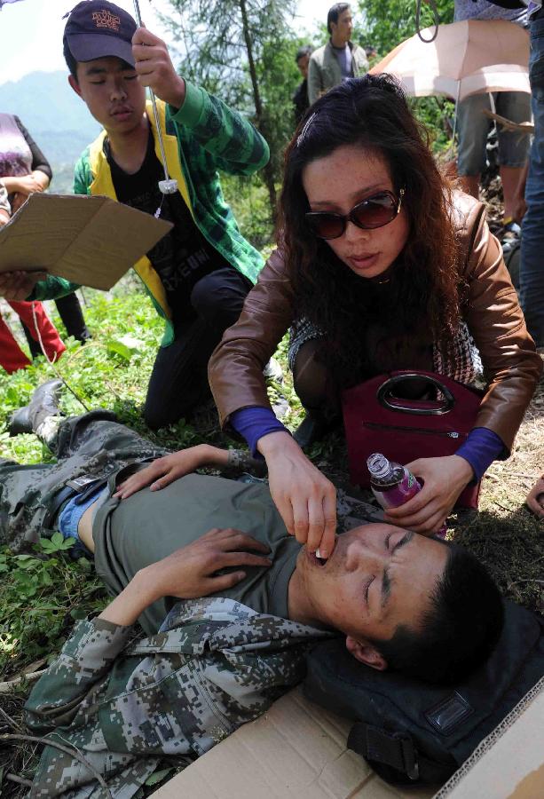 A woman gives medical treatment to a soldier saved from a rescue car from Chengdu Military Region which falls off a cliff into a river in southwest China's Sichuan Province, April 20, 2013. Two of the 17 soldiers in the car have died by 11:30 p.m. Saturday Beijing Time. A total of 156 people have been killed in the 7.0-magnitude earthquake in Sichuan's Lushan as of 8:50 p.m. Saturday, according to the China Earthquake Administration. (Xinhua) 