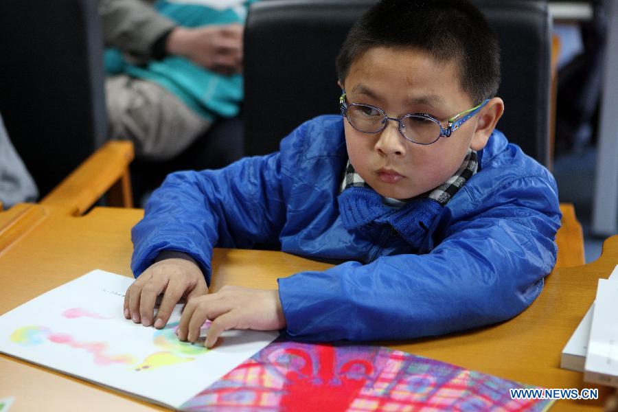 A visually impaired child reads a braille book during a reading party in the China Braille Library in Beijing, capital of China, April 21, 2013. A reading party for the visually impaired children was held here on Sunday. Li Yanyan, a visually-challenged physician who achieved a medical doctor degree at Palmer West College of Chiropractic in California, the U.S., participated in the reading party with his autobiography and shared his learning experience with the young readers and their parents. (Xinhua/Xu Zijian) 