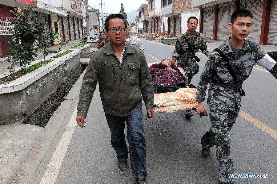 Soldiers and volunteers carry an injured person to the hospital in the Longmen Township, Lushan County, southwest China's Sichuan Province, April 21, 2013. Military and civilian rescue teams are struggling to reach every household in Lushan and neighboring counties of southwest China's Sichuan Province, badly hit by Saturday's strong earthquake. (Xinhua/He Junchang) 