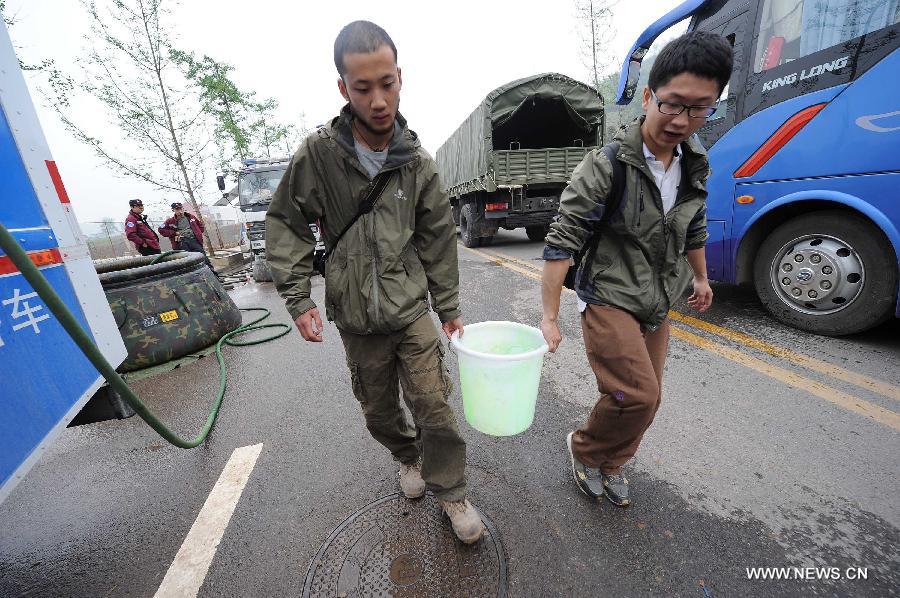 Rescuers carry drinking water to a temporary settlement in the quake-hit Lushan County, southwest China's Sichuan Province, April 22, 2013. The water and power supply were suspended after a 7.0-magnitude earthquake jolted Lushan County on April 20 morning. Rescue organizations are using water purification equipment to provide drinking water for affected local residents. (Xinhua/Li Jian)