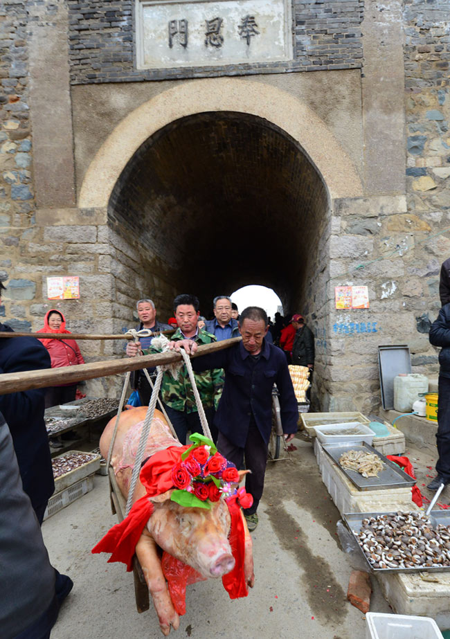 Fishermen carrying the sacrifice go through the gate of an ancient town on April 18, 2013. Xiongyasuo coastal ancient town is located in east of Jimo city in Shandong province. A temple fair is held in every march in lunar calendar before fishing to pray for the peace and prosperity. (Xinhua/Ning Youpeng)