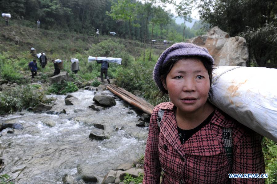 A woman carrying disaster relief supplies waits for her son as walking in the mountain in quake-hit Shifeng Village of Lushan County, southwest China's Sichuan Province, April 22, 2013. The road linking the Shifeng Village with the outside had been destroyed by a 7.0-magnitude earthquake on April 20. Local villagers set up a 300-member group to climb mountains to get relief supplies outside and then return to the village. Over 40 tonnes of materials had been transported and distributed to over 2,000 villagers. (Xinhua/Li Ziheng)