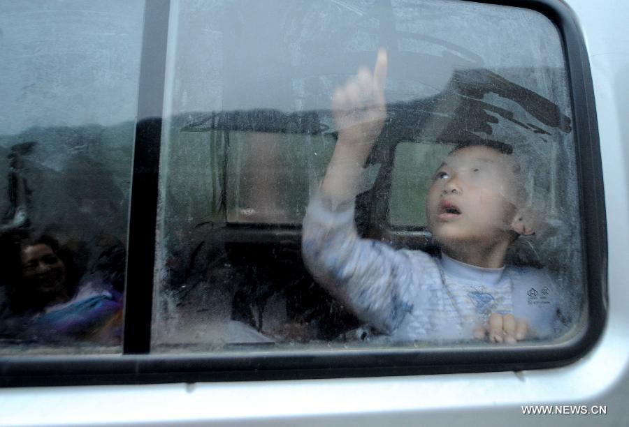 Guo Wenjie, a 6-year-old boy, scribbles on the window in a vehicle of his family in quake-hit Baoxing County of Ya'an City, southwest China's Sichuan Province, April 23, 2013. Guo's whole family consisting of five members lived in the vehicle these days after a 7.0-magnitude earthquake jolted Lushan County of Ya'an City on April 20. (Xinhua/Luo Xiaoguang)  