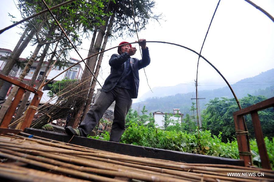 Villager Gao Kaimin, 50, makes use of a bed to build a tent in quake-hit Yuxi Village of Lushan County, southwest China's Sichuan Province, April 23, 2013. A 7.0-magnitude jolted Lushan County on April 20. (Xinhua/Xiao Yijiu)