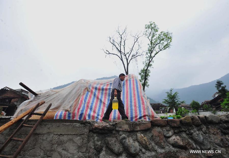 A villager transfers a bottle of cooking oil found in his house to the temporary settlement in quake-hit Yuxi Village of Lushan County, southwest China's Sichuan Province, April 23, 2013. A 7.0-magnitude jolted Lushan County on April 20. (Xinhua/Xiao Yijiu)