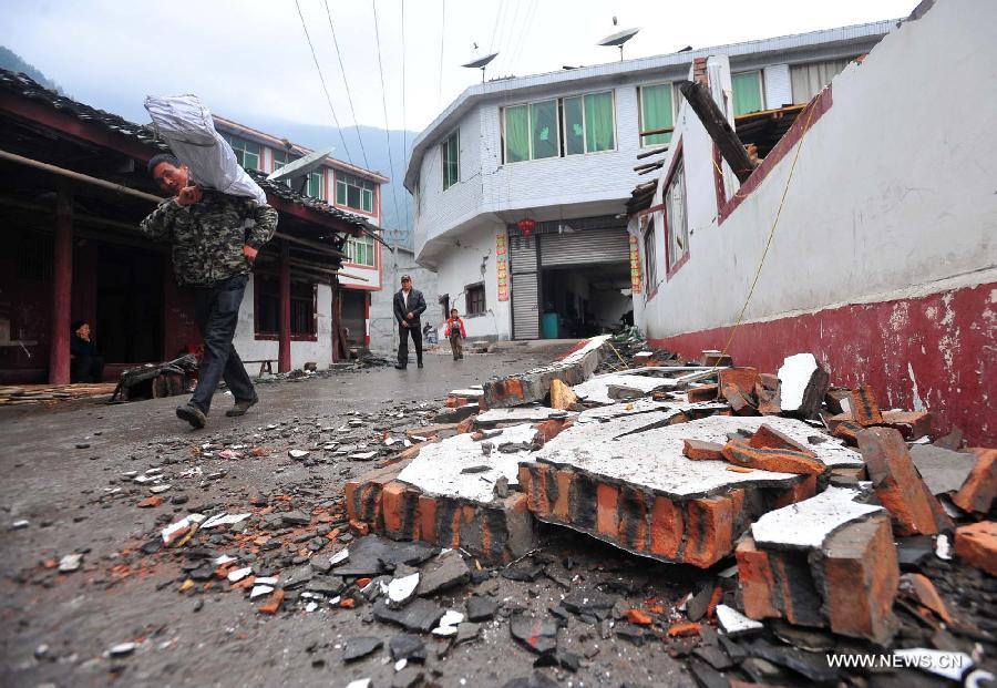 Villagers walk past a damaged house in quake-hit Yuxi Village of Lushan County, southwest China's Sichuan Province, April 23, 2013. A 7.0-magnitude jolted Lushan County on April 20. (Xinhua/Xiao Yijiu)