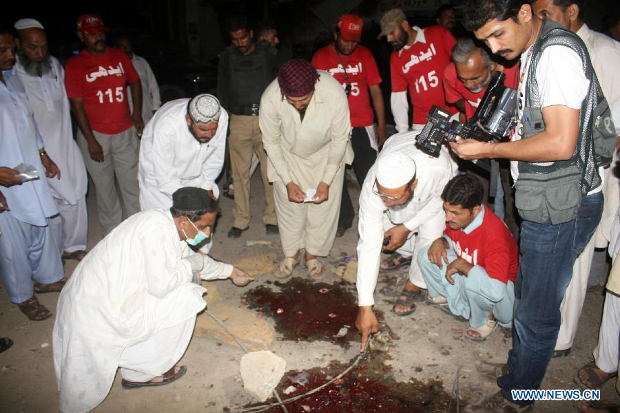 Security officials examine the blast site in southern Pakistani port city of Karachi on April 26, 2013. At least 11 people including a child were killed and 40 others injured on Friday night in a bomb blast that targeted a political meeting in Pakistan's southern port city of Karachi, local media and police said. (Xinhua/Masroor) 