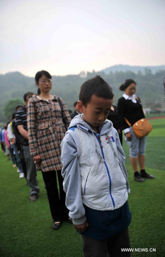 A young boy mourns for those who died in a 7.0-magnitude quake a week ago, at the playground of Lushan Middle School in Lushan County of Ya'an City, southwest China's Sichuan Province, April 27, 2013. Public mourning was held on Saturday morning in Sichuan Province for those who died in the earthquake on April 20. The quake has claimed nearly 200 lives. (Xinhua/Li Wen)