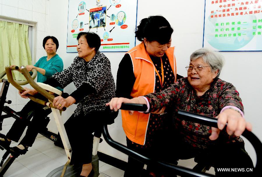 A community worker helps an old woman work on a gym equipment in Gulou District of Fuzhou, capital of southeast China's Fujian Province, April 28, 2013. A total of 435 community service centers have been set up in Fuzhou since 2008 to provide daily care and entertainment activities for senior citizens. (Xinhua/Zhang Guojun)