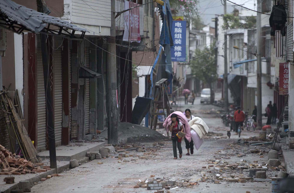 Two girls walk through quake-stricken street in Lushan County, Sichuan province, April 27, 2013. (Xinhua/Fei Maohua)