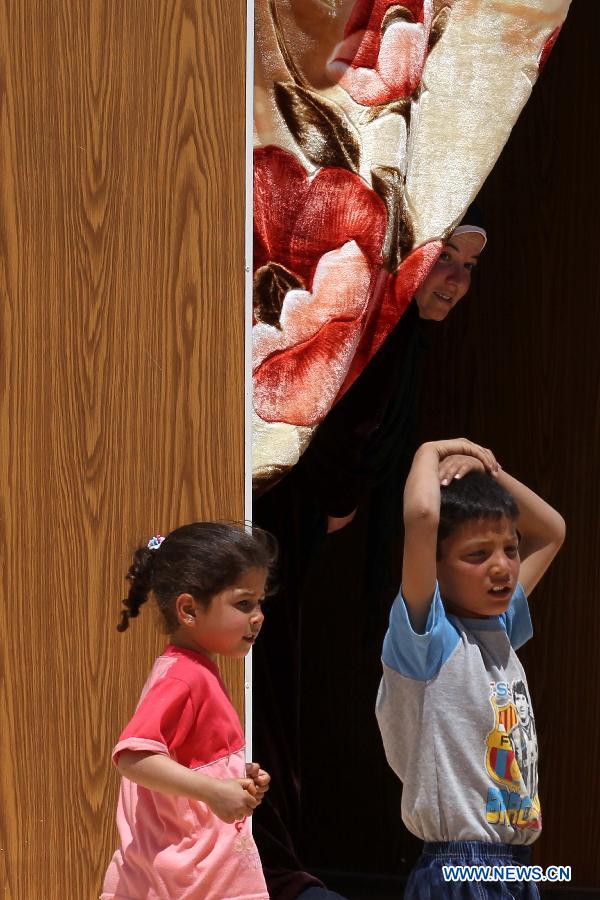 Syrian refugee children stand inside their family caravan at the Mrajeeb Al Fhood refugee camp, 20 km (12.4 miles) east of the city of Zarqa April 29, 2013. The Mrajeeb Al Fhood camp, with funding from the United Arab Emirates, has received about 2500 Syrian refugees so far, according to the Red Crescent Society of the United Arab Emirates. (Xinhua/Mohammad Abu Ghosh)