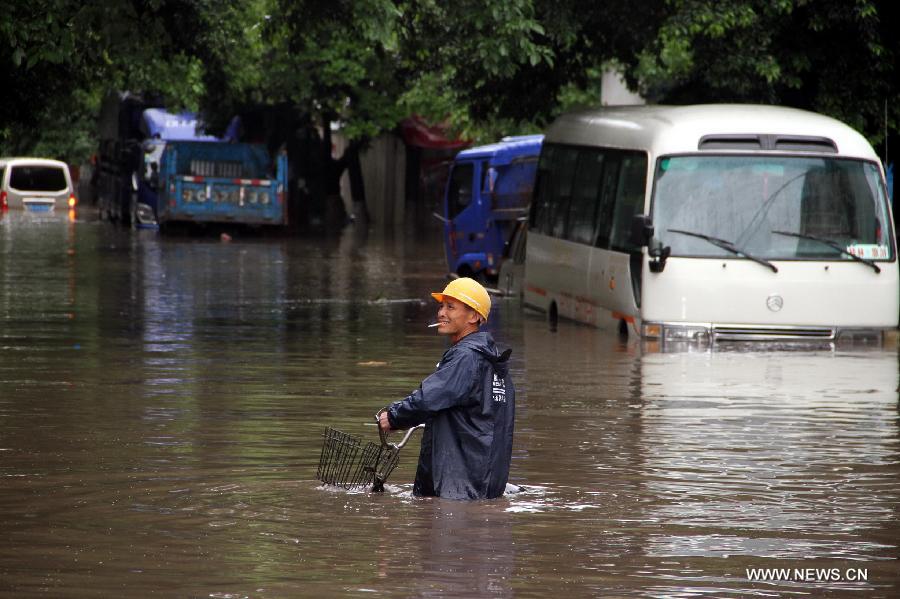 A rider pushes his bike in flood water in Guilin City, southwest China's Guangxi Zhuang Autonomous Region, April 30, 2013. Heavy rainfall hit Guangxi on April 29, making house damaged and causing floods and road cave-ins as well. (Xinhua/Ren Jiaxiang)