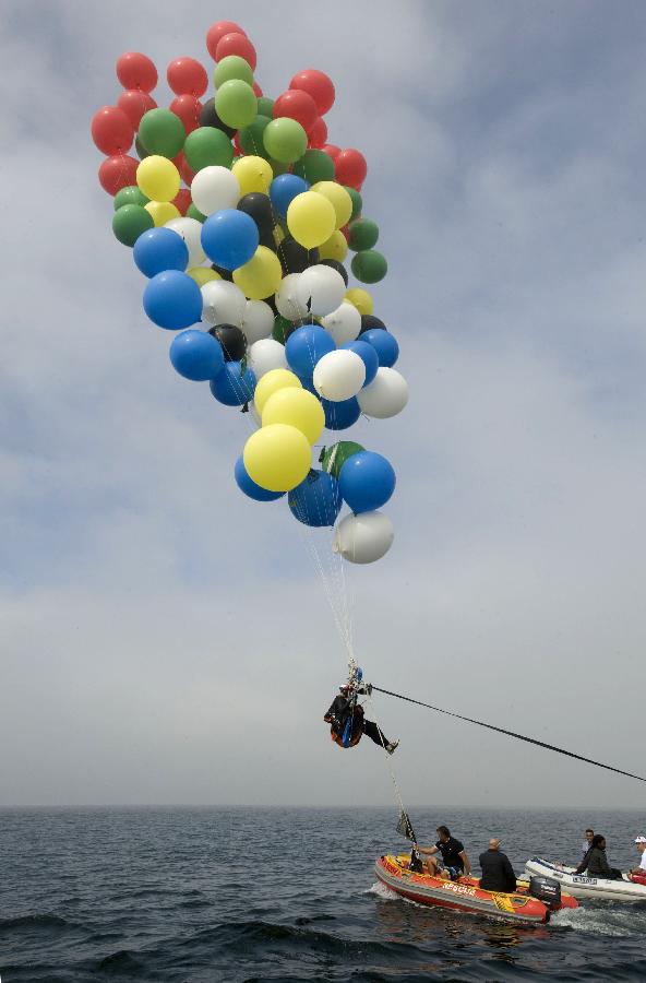 South African cluster balloonist Matt Silver-Vallance in mid air en route from Robben Island to the mainland near Cape Town, South Africa, April 6, 2013. The goal of Matt Silver-Vallance with his ballon trip is to raise 1 million U.S. dollars to help build a children's hospital named after 94-year-old Nelson Mandela, who became South Africa's first black president in democratic elections in 1994 after negotiating an end to white racist rule. (Xinhua/AFP Photo)