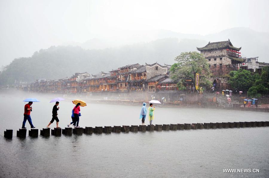 Tourists walk on rocks in Tuojiang River by the ancient town of Fenghuang in Fenghuang County of Xiangxi Tu and Miao Autonomous Prefecture, central China's Hunan Province, April 29, 2013. Fenghuang witnessed a rainfall on Monday, the first day of the three-day Labor Day holiday. (Xinhua/Zhao Zhongzhi) 