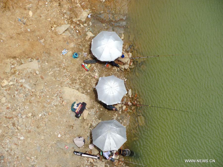 SHIYAN, May 2, 2013 (Xinhua) -- People under umbrellas fish on the naked riverbed at the Yunxian segment of the Hanjiang River in Yunxian County, central China's Hubei Province. The water level of the Hanjiang River in Yunxian County keeps declining since this spring due to the low rainfall, affecting the river's navigation. The water level here by 12 p.m. on May 1 stood at 137.49 meters, 19.65 meters less than the highest level of last year. (Xinhua/Cao Zhonghong)