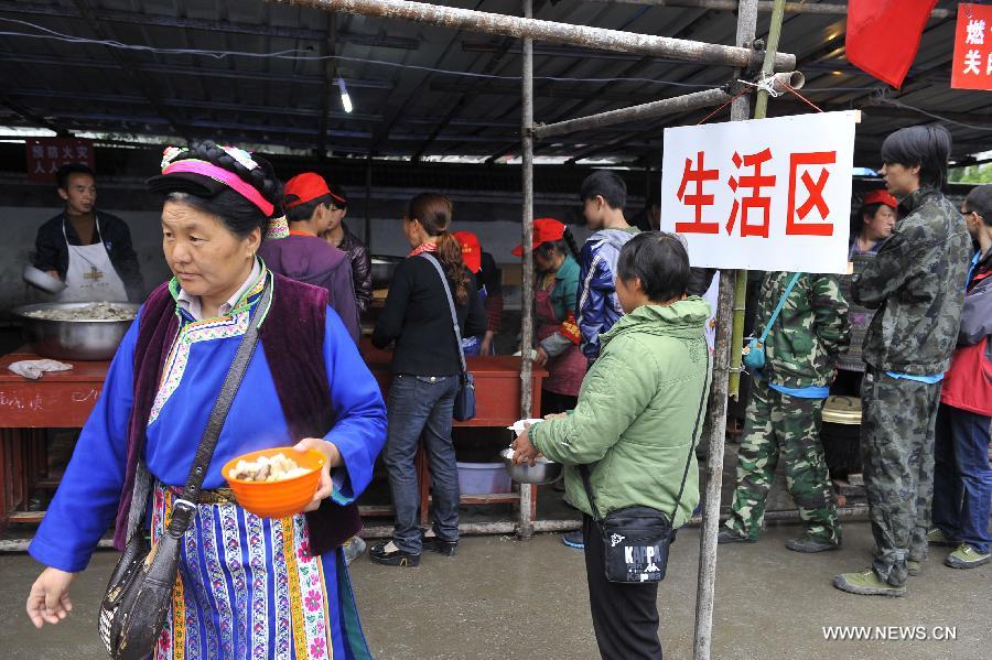 People receive free lunch at a school served as an evacuation settlement for displaced people in the quake-hit Baoxing County, southwest China's Sichuan Province, May 2, 2013. Some 4,000 displaced people live the settlement, the largest in the county, after a strong earthquake hit Baoxing last month. At present, basic living needs of those people could be guaranteed in terms of food, drink, healthcare service and power supply. (Xinhua/Lu Peng)