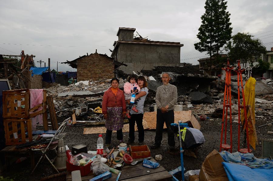 Zhang Qingyuan (1st R) and his family pose for a photo in front of their dismantled house, which was built in 2003 at a cost of some 100,000 yuan (about 16,234 U.S. dollars), at Longmen Township in quake-hit Lushan County, southwest China's Sichuan Province, May 2, 2013. On high alert for secondary disasters, dilapidated houses were dismantled lately after a 7.0-magnitude quake hit Lushan on April 20.(Xinhua/Jin Liangkuai)