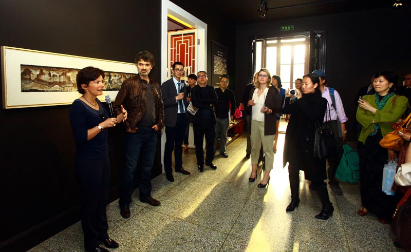 Christine Cayol, founder of Yishu 8 (1st, L) and Viktor Popov (2nd, L) introduce the exhibition to the public. (chinadaily.com.cn)