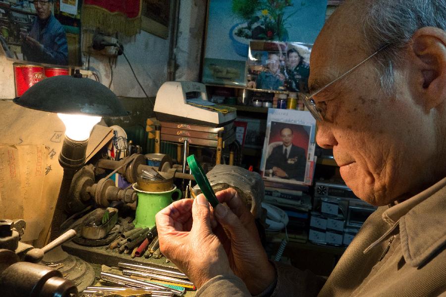 Zhang Guangyi examines a pen tip with a magnifier at his shop in Beijing, capital of China, April 24, 2013. (Xinhua/Xu Zijian)