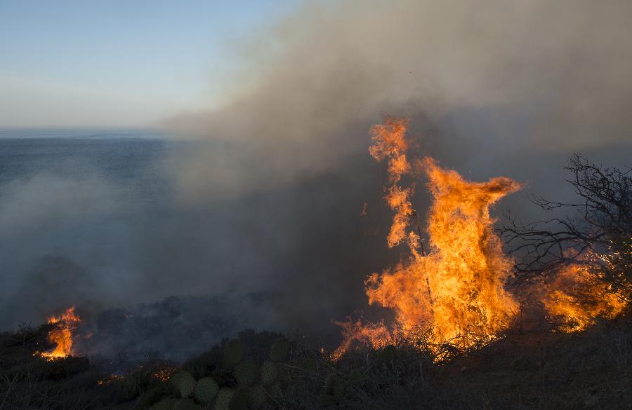 Thick smoke and blaze are seen near Malibu in California, the United States, May 3, 2013. The wind-driven wildfire forced the evacuation of a university campus and threatened some 4,000 homes in Southern California on Friday. (Xinhua/Yan Lei) 