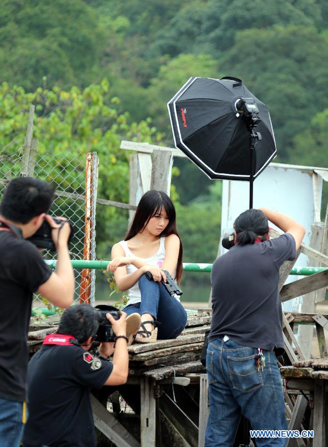 Photo taken on May 5, 2013 shows a woman poses for pictures near an abandoned house in Ma Wan, an island in south China's Hong Kong. Ma Wan, which got the name from Mazu, the goddess of sailors, used to be a fishing village. Now the Ma Wan Park and Noah's Ark Museum here attract many tourists. (Xinhua/Li Peng)