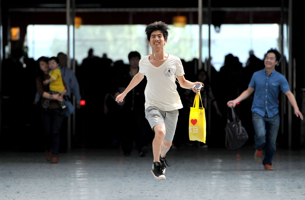 A young man runs out of the railway station leaving waves of travelers behind. A passenger flow peak is seen before the May Day holidays on April 28, 2013. (Xinhua Photo)