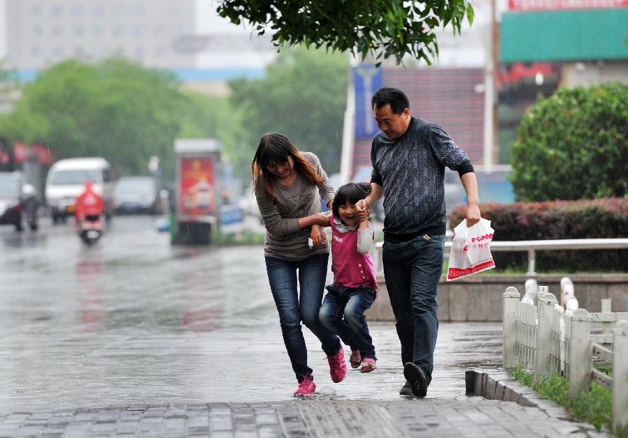 A family cross a water hole formed by rainwater in Yinchuan, capital of northwest China's Ningxia Hui Autonomous Region, May 7, 2013. The local meteorological observatory issued a yellow alert on thunderstorm on Tuseday as a thunderstorm hit Yinchuan the same day. (Xinhua/Peng Zhaozhi) 