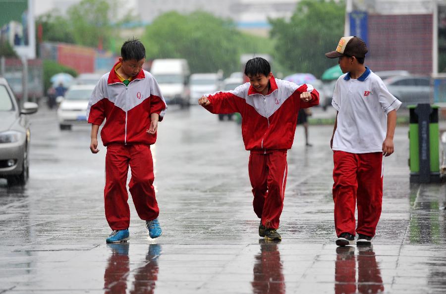 Several students walk in rain in Yinchuan, capital of northwest China's Ningxia Hui Autonomous Region, May 7, 2013. The local meteorological observatory issued a yellow alert on thunderstorm on Tuseday as a thunderstorm hit Yinchuan the same day. (Xinhua/Peng Zhaozhi) 