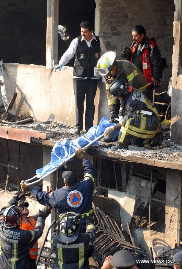 Firemen remove the body of a victim from the site of an explosion on the Mexico-Pachuca highway in Ecatepec, Mexico, on May 7, 2013. At least 20 people were killed and 34 injured when a gas tanker exploded early Tuesday in a Mexico City suburb, security officials said. (Xinhua/Susana Martinez) 