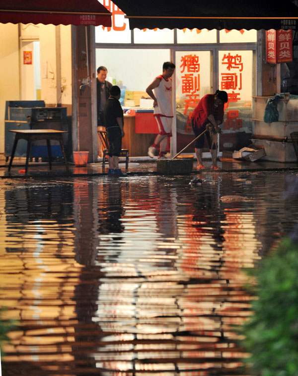 A passenger takes off his shoes and wades through the rain-drenched street in Changsha, capital of Central China's Hunan province on May 7, 2013. [Photo /Xinhua]