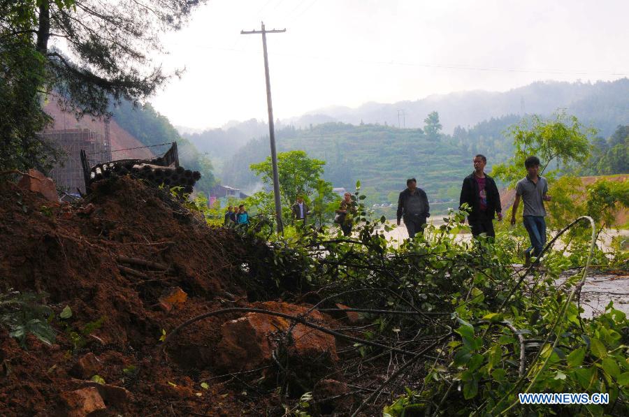 People walk past a site where a collapse took place due to storms in Yindong Village of Jinping County, southwest China's Guizhou Province, May 7, 2013. The central, south central and southeast parts of Guizhou were hit by hails and storms from Monday to Tuesday, disturbing local traffic and power service and causing damage to agricultural production. (Xinhua/Yang Xiuting)