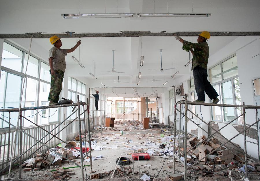 Workers dismantle a severely damaged wall in Lushan Middle School of Ya'an City, southwest China's Sichuan Province, May 8, 2013. Renovation and consolidation of damaged schoolhouses are underway in Lushan Middle School after the 7.0-magnitude earthquake on April 20, 2013. The whole repair process may last for two months. (Xinhua/Li Hualiang)