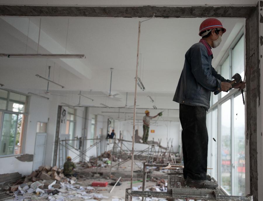 Workers dismantle severely damaged walls in Lushan Middle School of Ya'an City, southwest China's Sichuan Province, May 8, 2013. Renovation and consolidation of damaged schoolhouses are underway in Lushan Middle School after the 7.0-magnitude earthquake on April 20, 2013. The whole repair process may last for two months. (Xinhua/Li Hualiang)