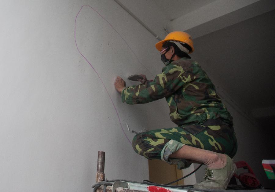 A worker marks a wall to be dismantled in Lushan Middle School of Ya'an City, southwest China's Sichuan Province, May 8, 2013. Renovation and consolidation of damaged schoolhouses are underway in Lushan Middle School after the 7.0-magnitude earthquake on April 20, 2013. The whole repair process may last for two months. (Xinhua/Li Hualiang)